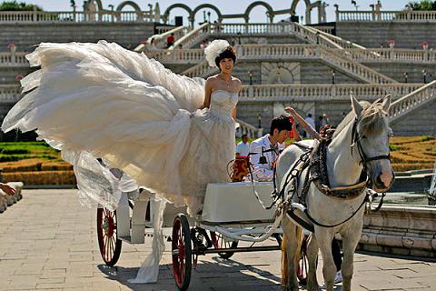 一名中国新娘正等待她的新郎做好发型拍婚纱照