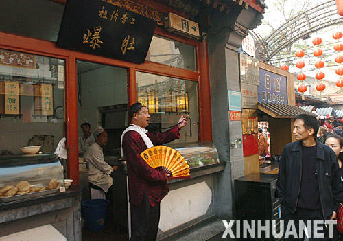 “店小二”身着古装站在北京王府井小吃一条街招徕客人（10月24日摄）。
